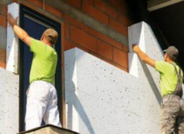 Apartman dış cephesine mantolama yapan ustalar ısı yalıtım levhası uyguluyor