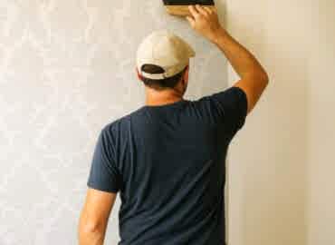 Salon duvarına dekoratif duvar kağıdı döşeyen usta